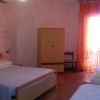 Camera con letto matrimoniale, due letti singoli, armadio, tende arancioni.