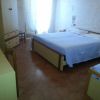 Camera con letto matrimoniale, tende chiare, armadio e pavimento in piastrelle.
