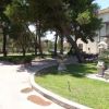 Area verde con statue, alberi e panchine vicino a un edificio.