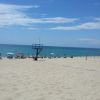 Spiaggia deserta con mare calmo e poche sedie a sdraio sotto ombrelloni.