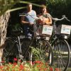 Due biciclette con cestini, persone e fiori.