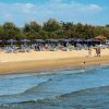 Spiaggia sabbiosa con ombrelloni blu.