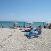 Spiaggia ghiaiosa con ombrelloni colorati.