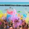 Persone lanciano polveri colorate su una spiaggia.
