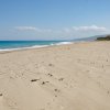 Spiaggia deserta con cielo sereno e mare azzurro.