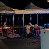 Persone sedute sotto gazebo in spiaggia di notte.