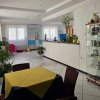 Sala con tavolo apparecchiato, piante e vetrina espositiva vicino a un desk bianco.