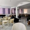 Sala con sedie in vimini e pianoforte. Finestre con tende viola.