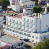 Un edificio bianco a più piani con balconi e tetto rosso su una strada cittadina.