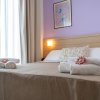Stanza con letto matrimoniale, asciugamani piegati e parete lilla.