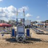 Spiaggia con sdraio blu e gialle, ombrelloni e cielo nuvoloso.