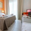 Una camera d'albergo con letto matrimoniale, letto singolo, TV e balcone.