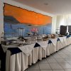 Buffet con tovaglie bianche e blu e un murale di tramonto sul mare.