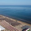 Spiaggia con file di ombrelloni e mare calmo.